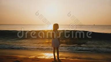 在令人难以置信的金色海洋日落海滩，快乐的小女孩观看海浪<strong>来袭</strong>的电影后景拍摄。